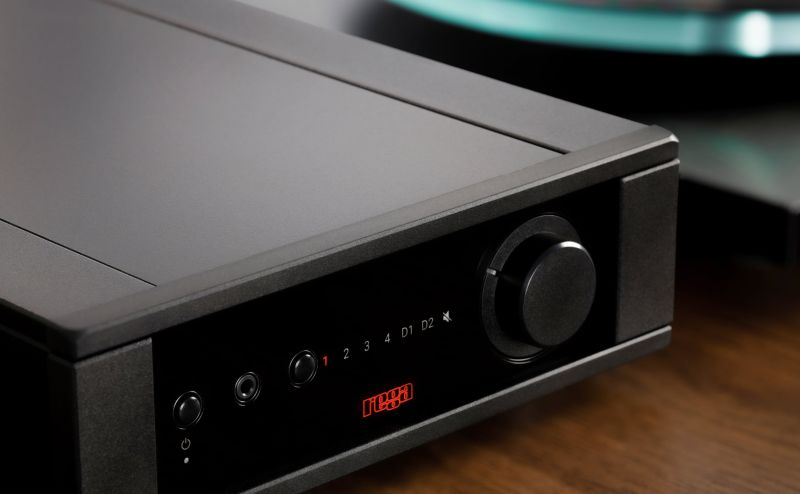 The Brio MK7 fascia photographed close on a wooden surface, input markers 1 to 4, D1 and D2 and the mute symbol lit in red beside the volume knob