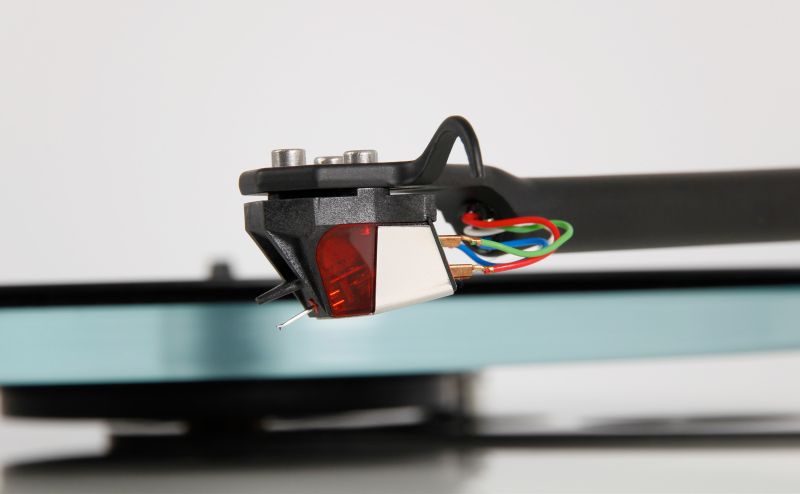 The Nd3 mounted on a Rega tonearm above a pale blue glass platter, tag wires curving back to the arm tube