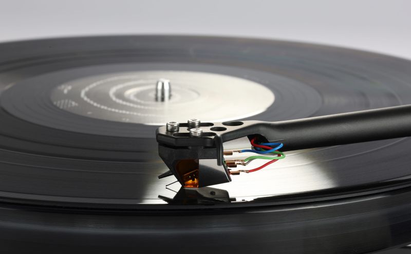 The Nd9 tracking a black record from above, the amber body and tag wires lit against the grooves and the spindle beyond