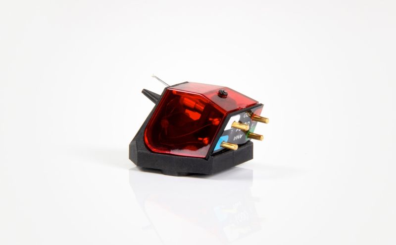 The Ania Pro in studio three-quarter view, translucent red rigid cover over the generator on a black body, gold pins at the rear