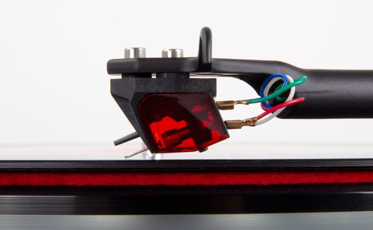 The Ania Pro on a Rega arm above a record with a red felt mat, headshell bolts and colour-coded tag wires in view
