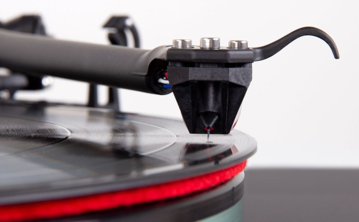 The arm lowered onto the platter seen from the front, the Ania Pro and its stylus above the red mat and the record edge