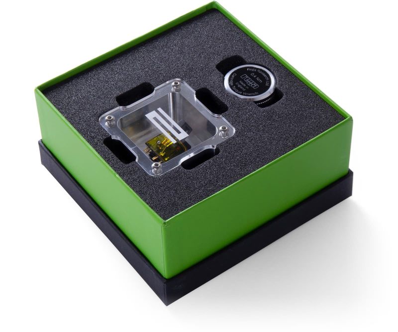 The Aphelion 2 in its green presentation box, the cartridge in a clear acrylic case set in black foam beside a round badge