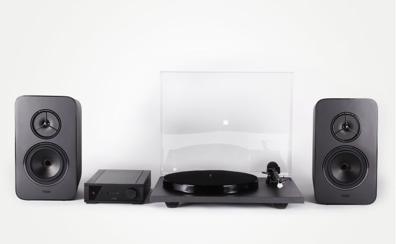 The complete Rega System One against white, a Kyte loudspeaker each side, the io amplifier left of centre and the Planar 1 turntable with its lid closed
