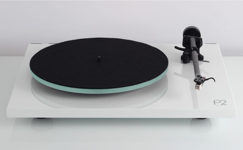 Planar 2 in high gloss white seen low from the side, the glass platter edge under the mat